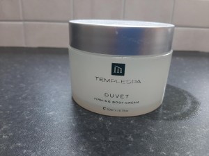 Photo of an empty jar of Temple Spa Duvet firming body lotion on worktop.